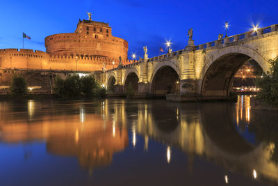 Arch bridge over river against buildings