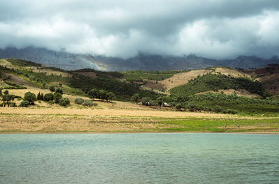 Scenic view of river by mountains against sky
