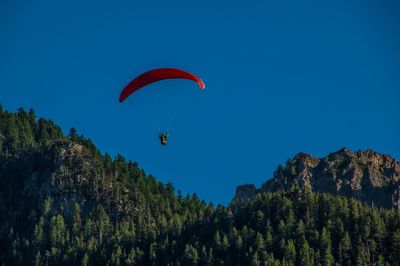 Person paragliding against clear blue sky