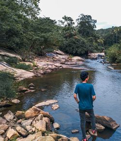 Rear view of man on rock by river