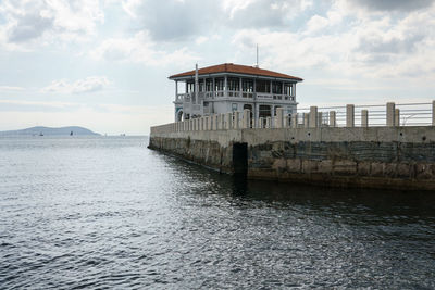 View of building by sea against cloudy sky