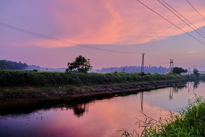 Reflection of electricity pylon against sky during sunset