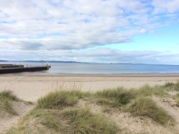 Scenic view of beach against cloudy sky