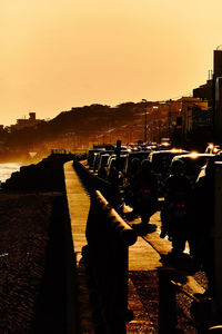 People on street by city against orange sky