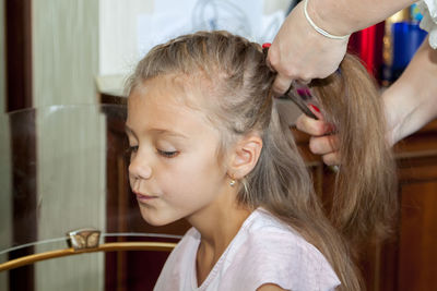 Cropped hand of mother tying daughters hair