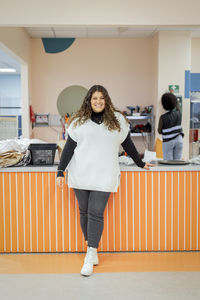 Smiling female worker standing near counter at recycling center