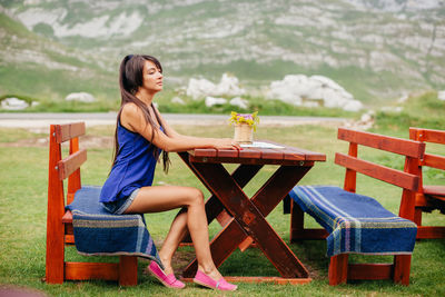 Side view of mid adult woman sitting on bench