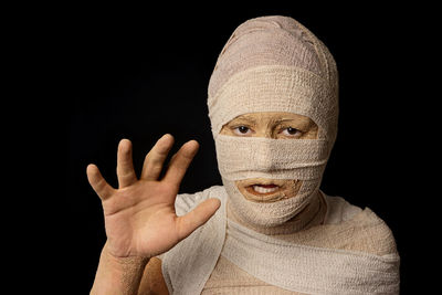 Portrait of woman wrapped with bandages against black background