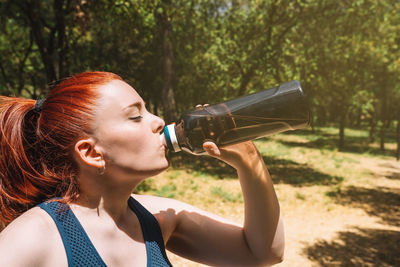 Woman drinking water in forest