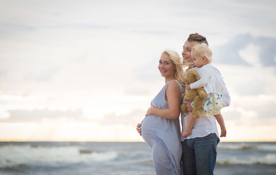 Family at beach against sky during sunset