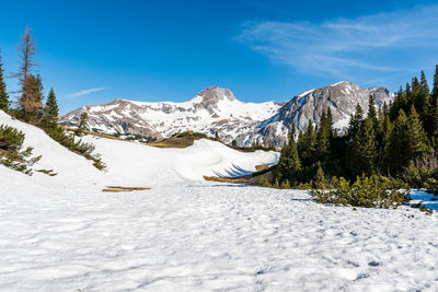 Scenic view of snow covered mountains against blue sky