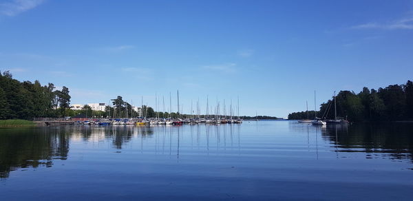 Sailboats moored in lake against blue sky