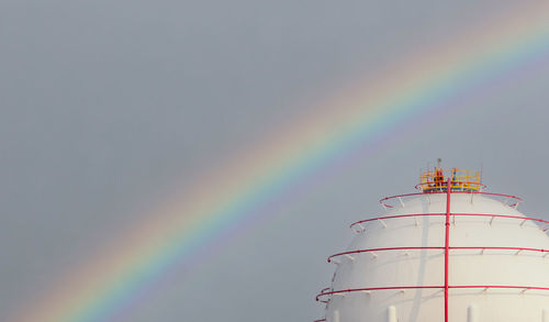 Low angle view of rainbow over buildings against sky