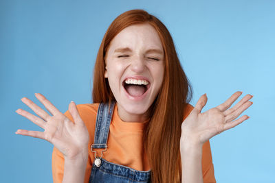 Cheerful woman screaming against blue background