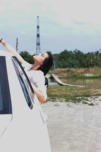 Woman standing by car against sky
