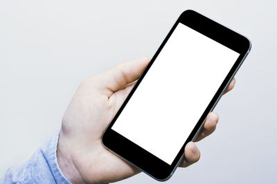 Low section of person holding smart phone over white background