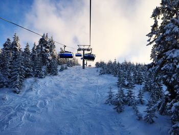 Ski lift over snow covered mountain against sky