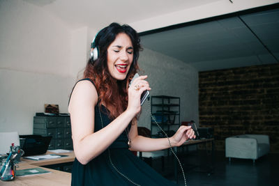 Young woman with headphones singing in office