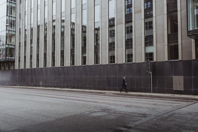 Businessman walking on sidewalk against wall in city