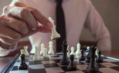 Midsection of businessman playing chess in office