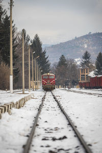 Snow covered railroad tracks against sky during winter