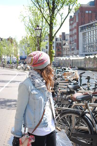 Rear view of man standing on bicycle in city