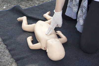 Midsection of paramedics performing cpr on baby mannequin