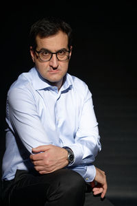 Mid adult man wearing eyeglasses against black background