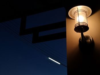 Low angle view of illuminated lamp against blue sky