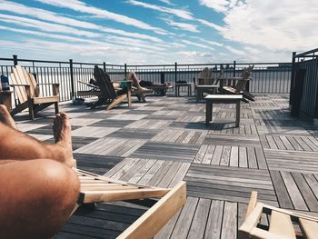 Low section of man on railing against sky