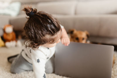 Cute girl touching laptop with dog at home