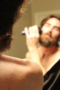 Close-up of mid adult man shaving reflecting on mirror at home