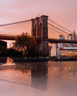 View of suspension bridge over river at sunset