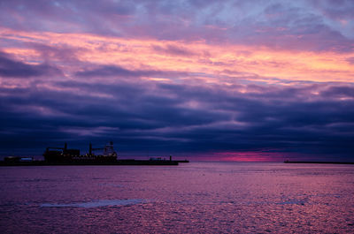 Scenic view of sea against dramatic sky during sunset