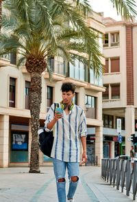 Young afro-haired man is walking down the street looking at his mobile