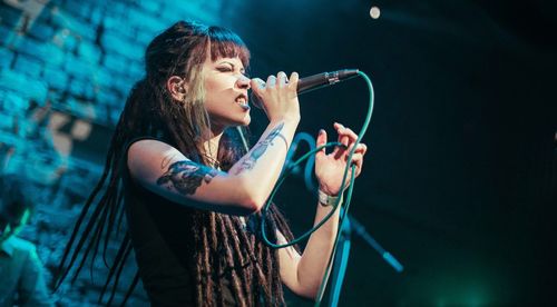 Side view of young woman singing by microphone