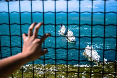 Close-up of hand against sea