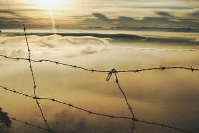 Silhouette barbed wire against sky during sunset