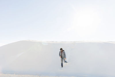 Man walking at white sands national monument against sky on sunny day