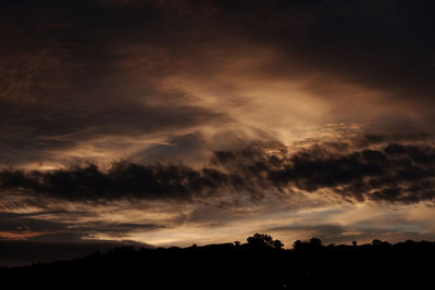 Low angle view of silhouette trees against dramatic sky