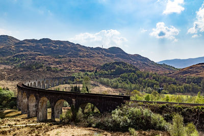 Arch bridge over mountains against sky