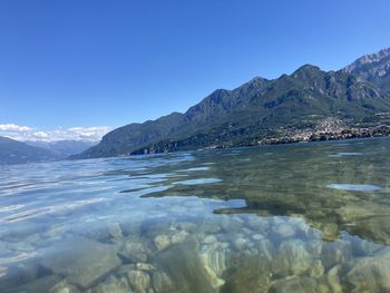 Scenic view of lake and mountains against clear blue sky