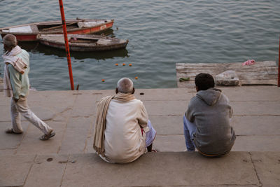 Rear view of men sitting on boat in sea