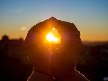 Close-up of woman holding sun during sunset