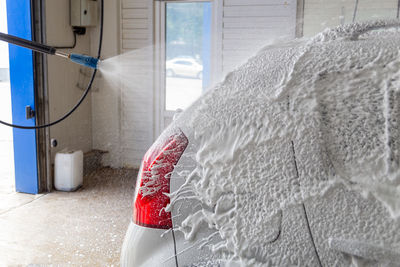 Soap detergent foam application process while washing indoors at self-service carwash station