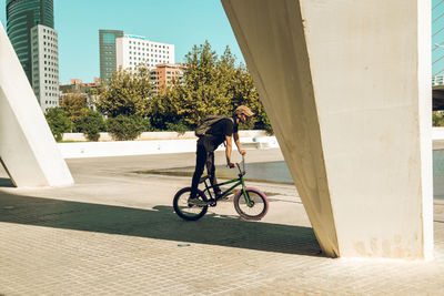 Side view of man riding bicycle against building