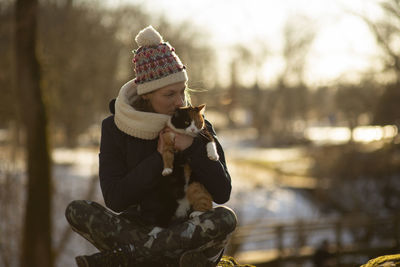 Young woman relaxing yoga pose and holdig cat during winter or early spring morning