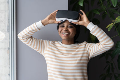 Happy joyful afro woman taking vr helmet off, black gemale using virtual reality glasses at home