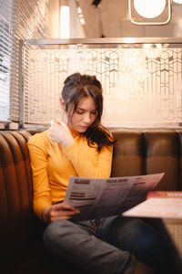 Teenage girl looking at menu while sitting in restaurant