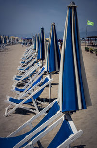 Panoramic view of deck chairs on beach against blue sky